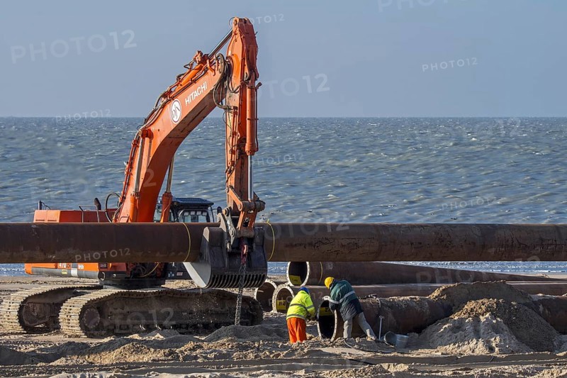 Dredging workers connecting pipes of pipeline during sand replenishment