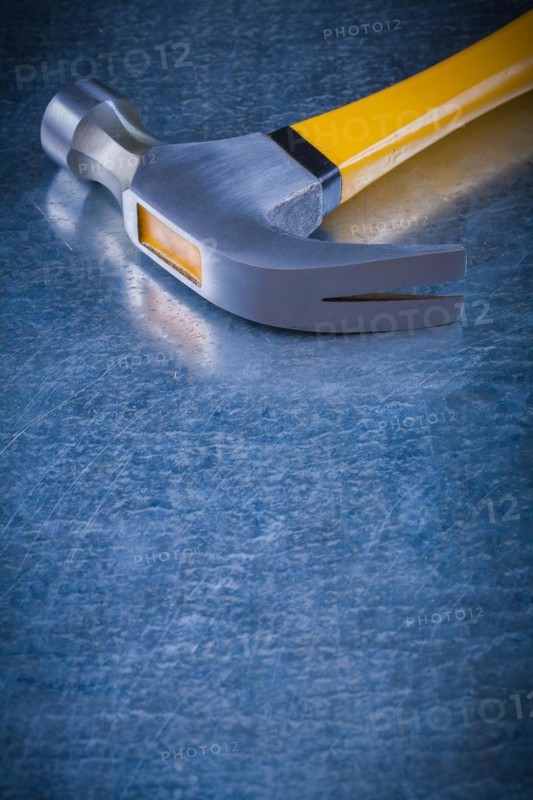Close up image of claw hammer on scratched vintage metallic background construction concept