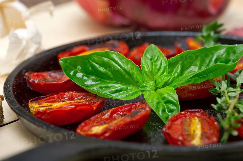 Oven baked cherry tomatoes with basil and thyme on a cast iron skillet