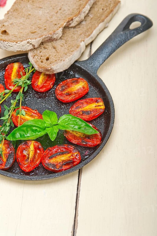 Oven baked cherry tomatoes with basil and thyme on a cast iron skillet