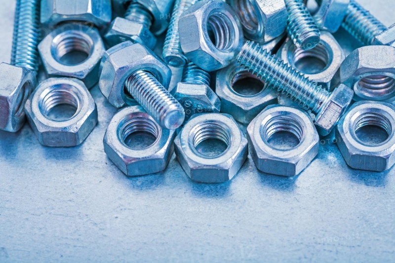 Pile of metal bolts and nuts on a metallic background Construction concept