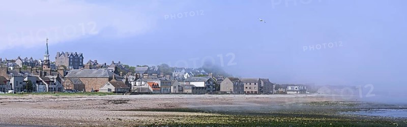 Shingle beach covered in mist and the town Stonehaven