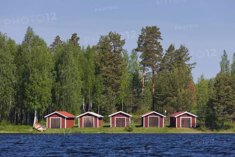 Red wooden boathouses along lake Siljan in summer