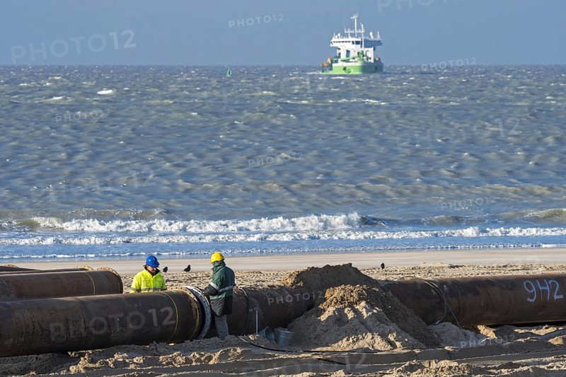 Dredging workers connecting pipes of pipeline during sand replenishment