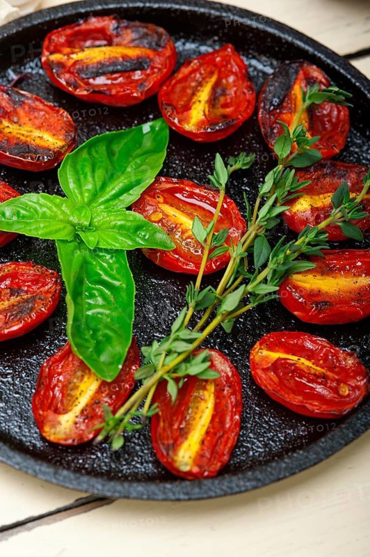 Oven baked cherry tomatoes with basil and thyme on a cast iron skillet