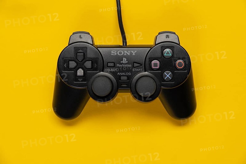 Controller of the PS2 Playstation game console from Sony in front of a monochrome yellow background