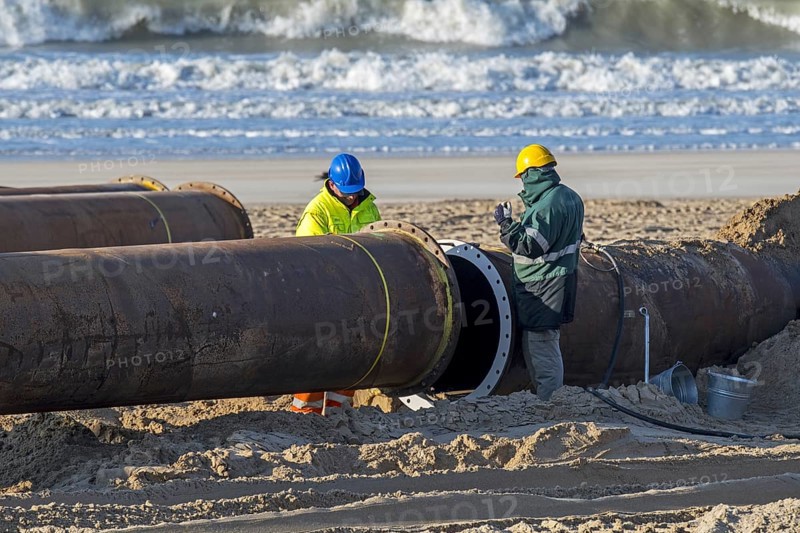 Dredging workers connecting pipes of pipeline during sand replenishment