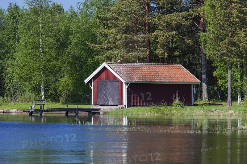 Red wooden boathouses along lake Siljan in summer