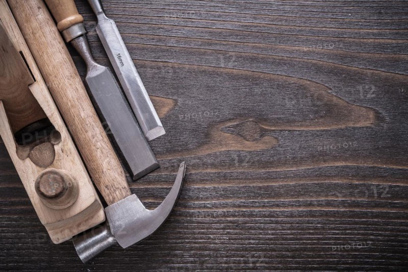 Composition of claw hammer wooden razor plane and flat chisel on vintage wooden board construction concept