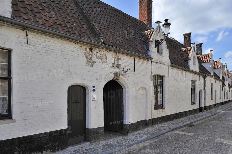 Almshouses along cobbled alley in Bruges