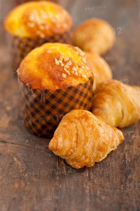 Fresh baked muffin and croissant mignon on old wood table