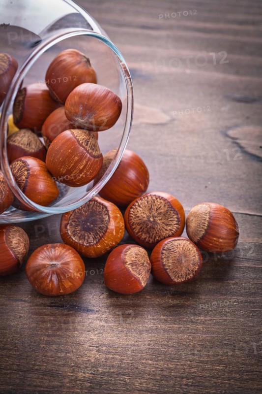 Stack of hazelnuts in a glass bowl on a vintage wooden board Food and drink Still life