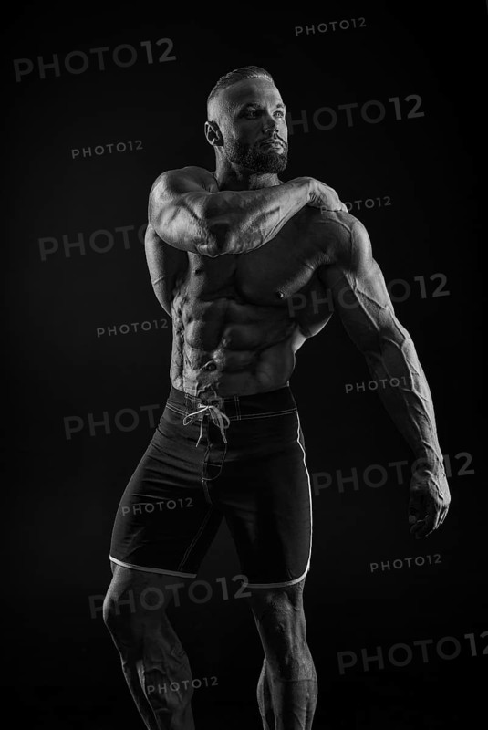 Silhouette of a strong bodybuilder. Confident young fitness athlete with a powerful body and perfect abs. Black and white photography. Dramatic light. Mixed media