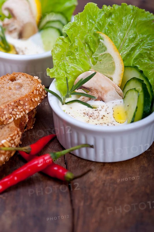 Fresh organic garlic cheese dip salad on a rustic table with bread
