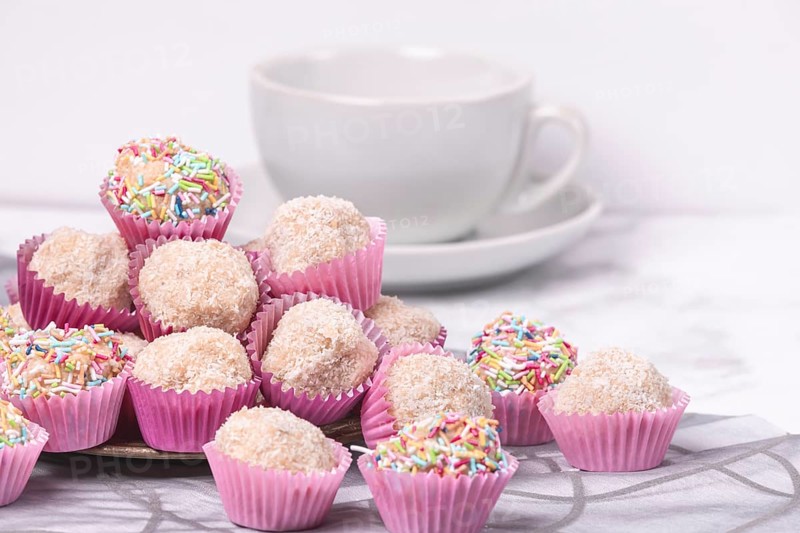 Light rum balls in pink paper cups with colourful sprinkles and coconut