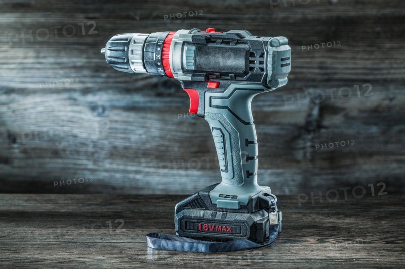 Electric tools cordless hand drill on vintage wooden background