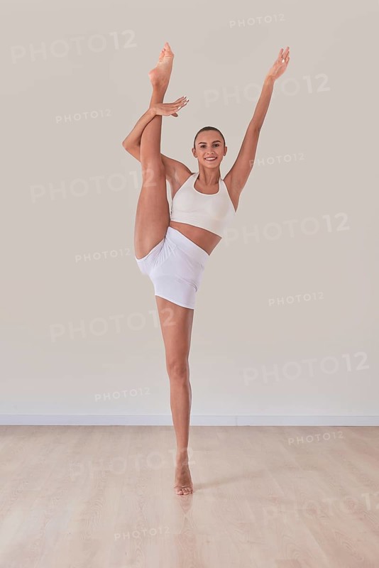 Flexible woman is training in a light studio. The concept of gymnastics