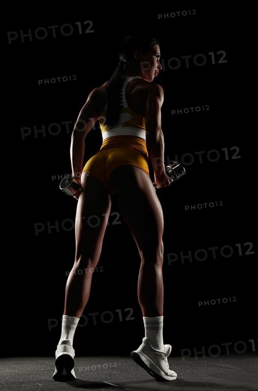 Brutal sports woman pumps up muscles with dumbbells. Fitness concept. Mixed media