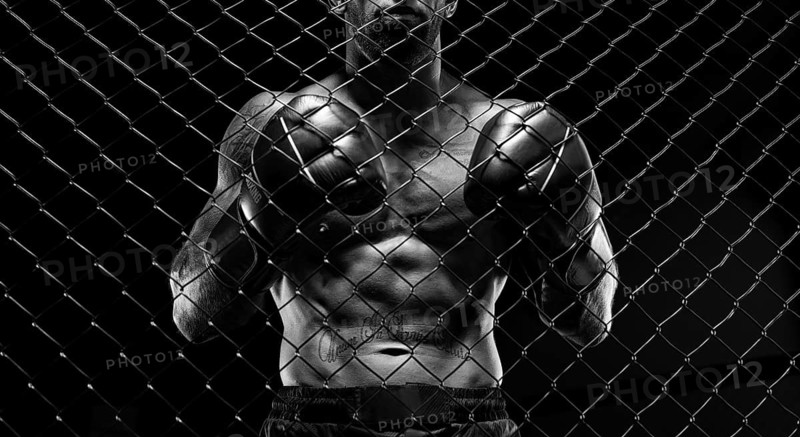 Black and white image of a man in a boxing cage. The concept of sports