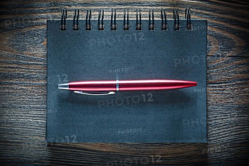Black notebook pen on vintage wooden board top view