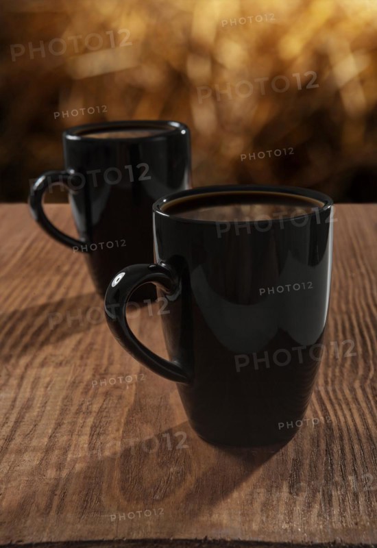 Black cups with coffee on an old wooden board