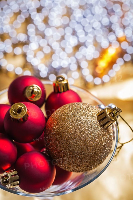 Golden and red Christmas baubles in a wine glass up close