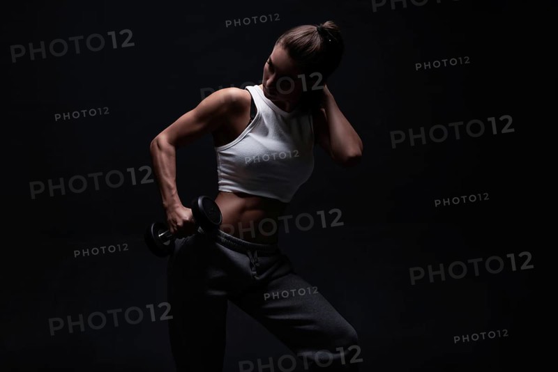 Athletic fitness woman posing in the studio on a dark background. Photo of an attractive woman in fashionable sportswear. Sports and healthy lifestyle. Mixed media