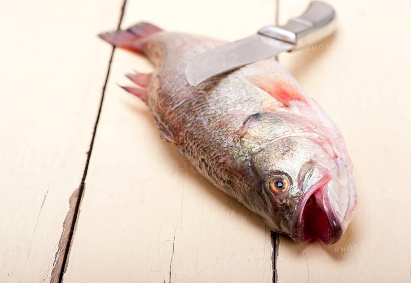 Fresh whole raw fish on a wooden table ready to cook