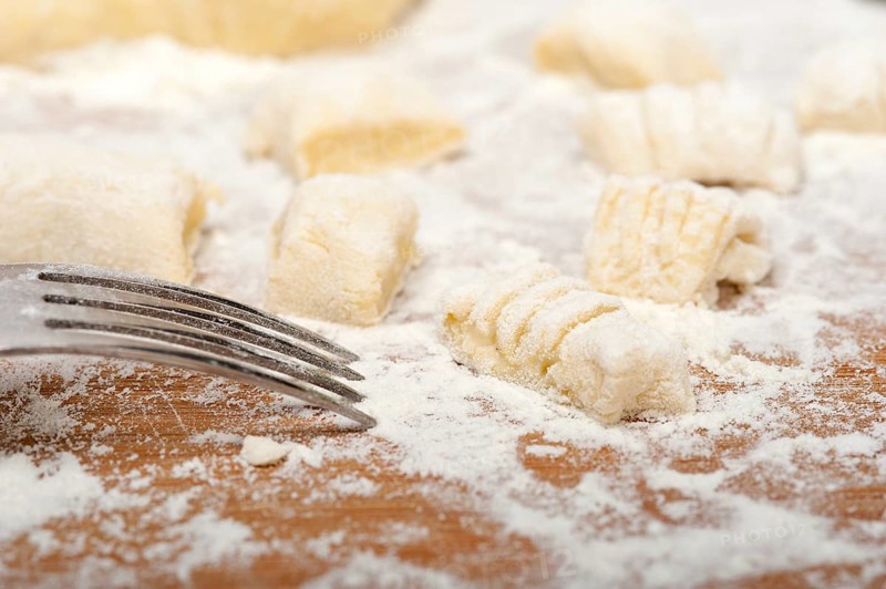 Making fresh Italian potato gnocchi on a wood rustic table