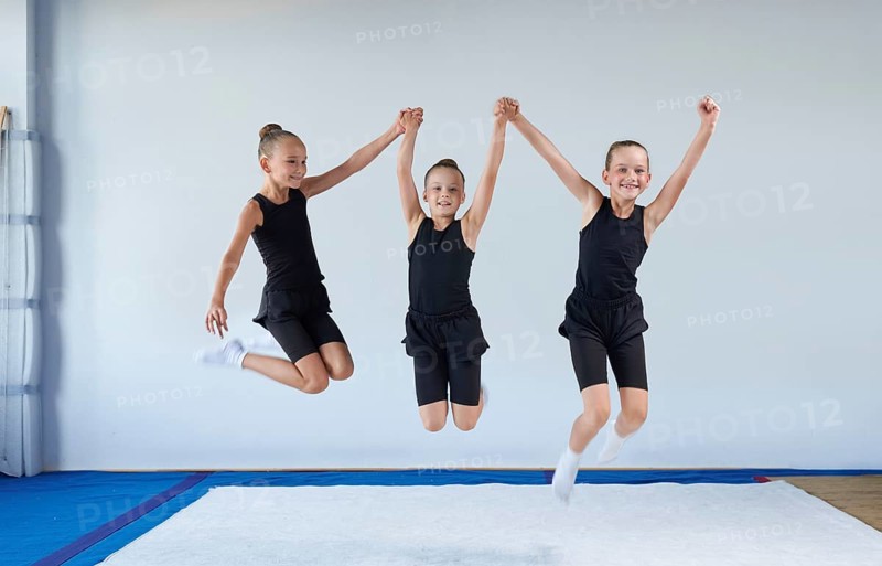 Group of cheerful children are jumping in the gym. Gymnastics concept. Mixed media