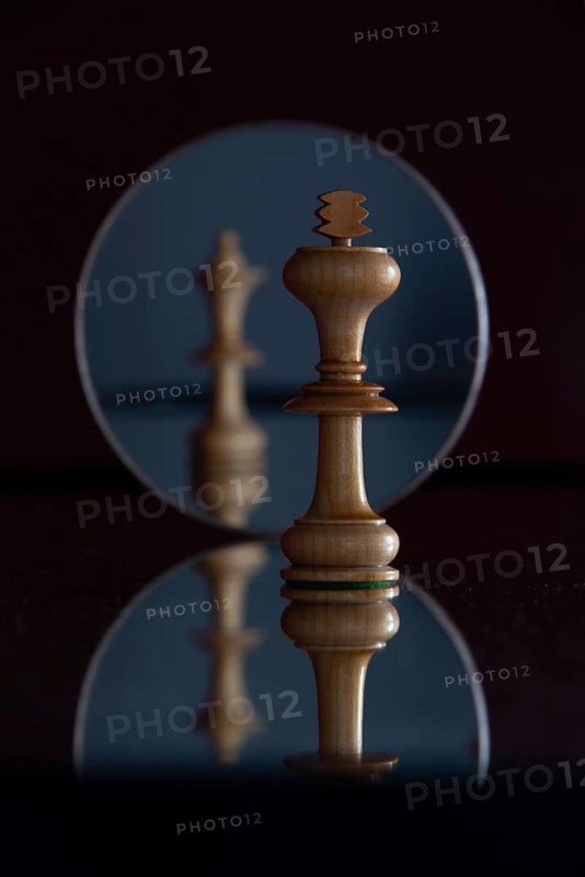 Reflection of a queen chess piece in a mirror