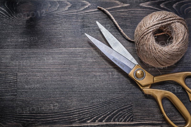 Golden scissors skein of rope on vintage wooden board