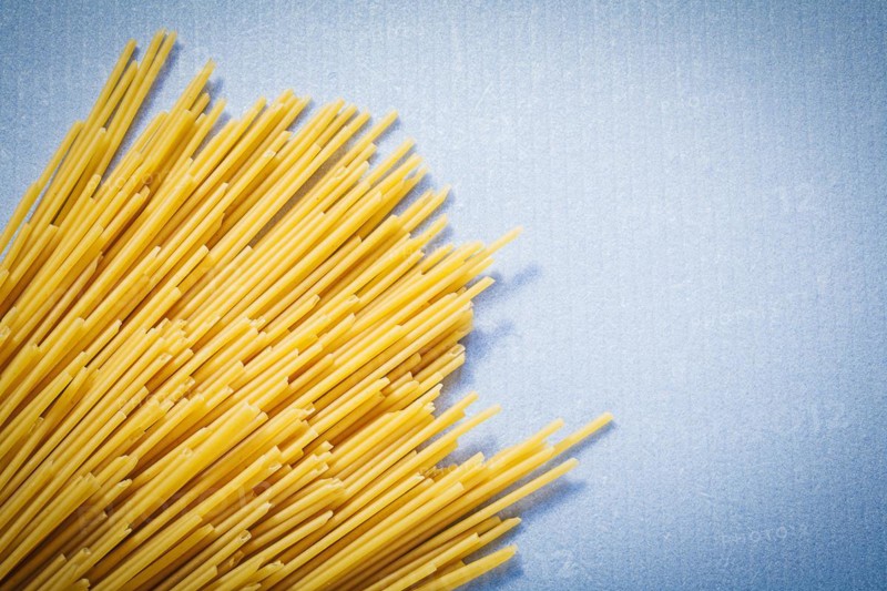 Yellow thin spaghetti on blue background food and drink concept