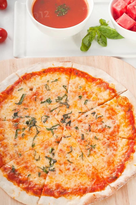 Italian original thin crust pizza Margherita with gazpacho soup and watermelon on side