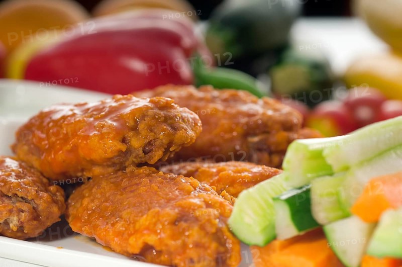 Classic buffalo chicken wings served with fresh pinzimonio and vegetables on background