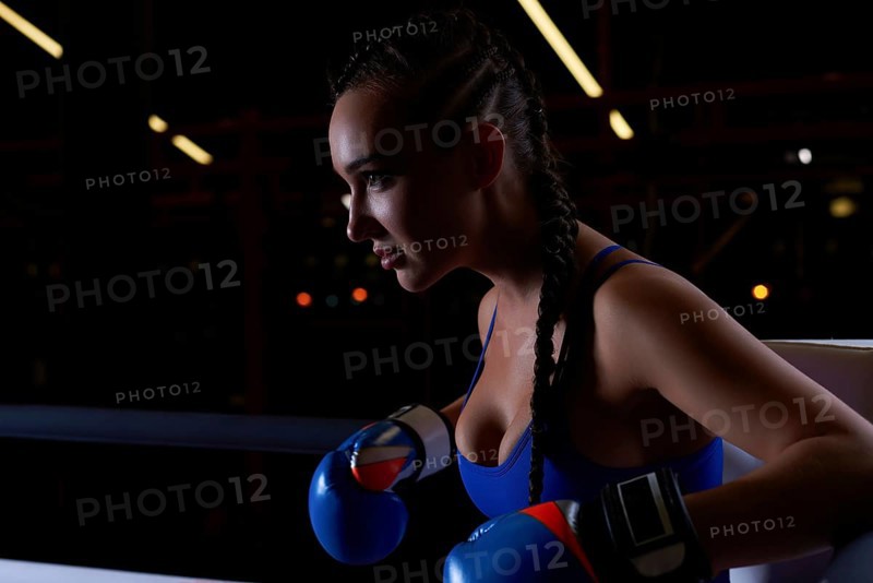 Powerful charged girl stands in the corner of the ring and is ready to explode in the next round. The concept of wrestling and boxing. Mixed media