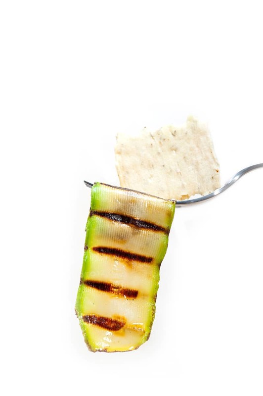 Grilled zucchini courgette on a fork with cracker macro close up