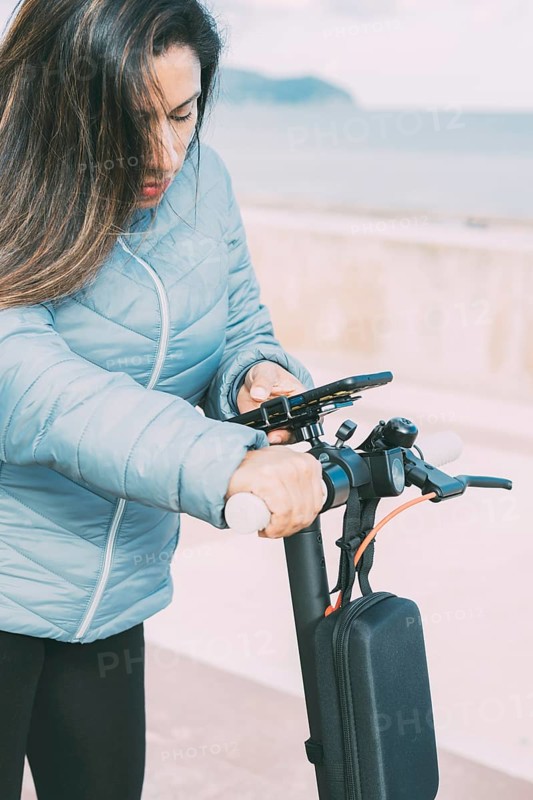 Side view of Beautiful latin woman riding her motorized scooter in the city