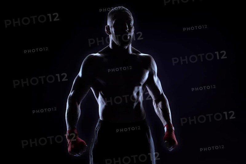 Kickboxer in red bandages posing on a blue background. The concept of mixed martial arts. MMA