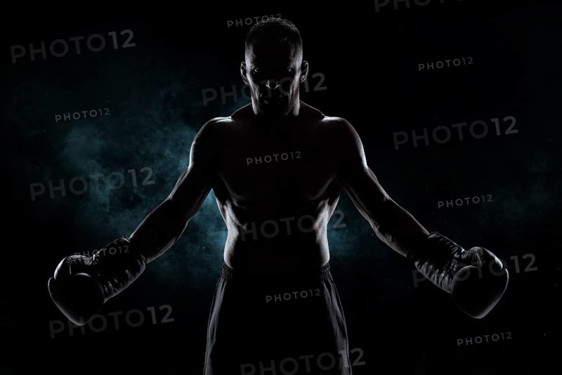 Kickboxer in black gloves posing on a background of smoke. The concept of mixed martial arts. MMA