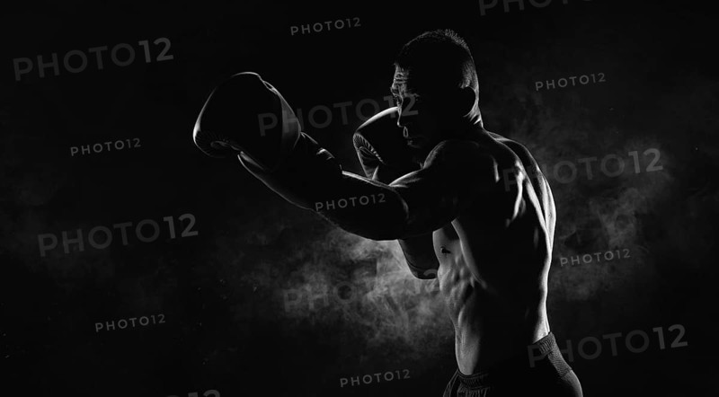 Kickboxer in black gloves posing on a background of smoke. The concept of mixed martial arts. MMA