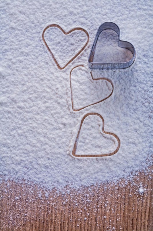 Cookie cutter in the shape of a heart on flour and wooden board Food and drink concept