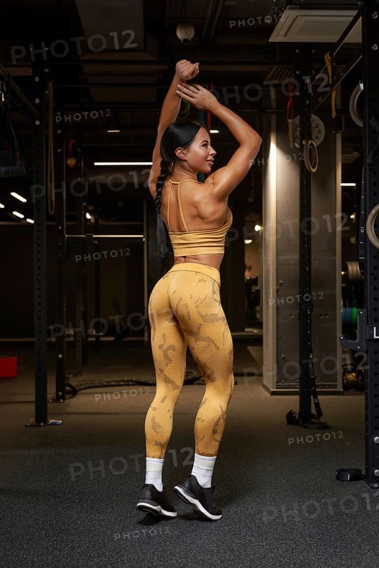Sexy fitness woman. A beautiful athletic girl posing in the gym in a yellow training suitl. Sports and fitness concept