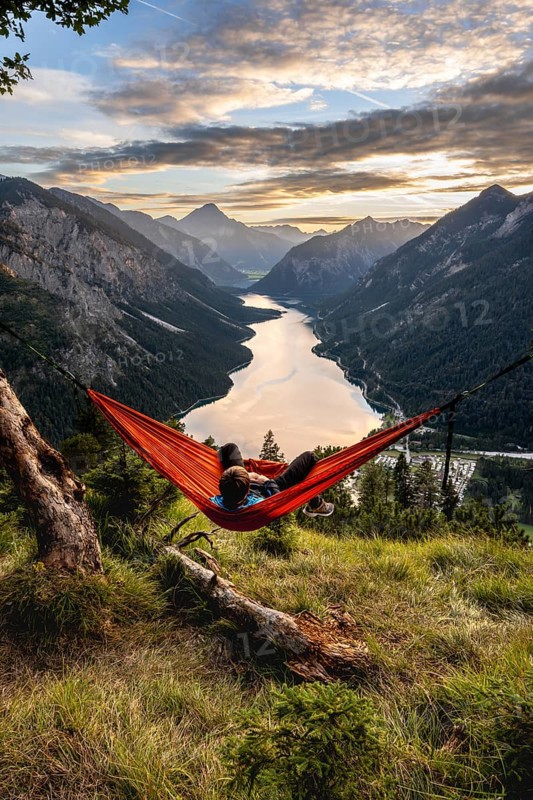 Young man sitting in an orange hammock