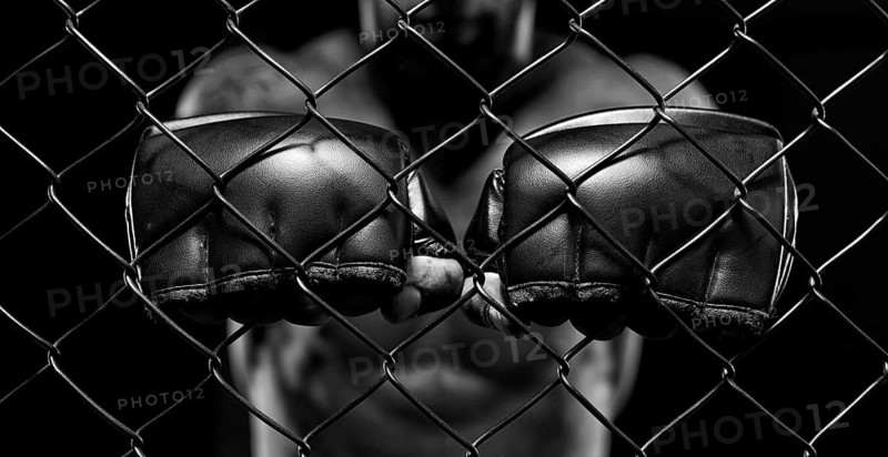 Black and white image of a man in a boxing cage. The concept of sports