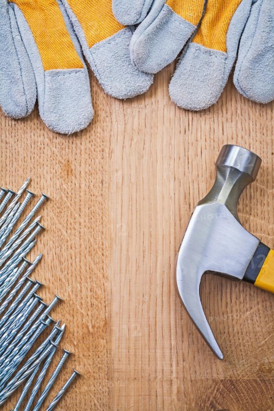 Copyspace image claw hammer nails protective gloves on wooden board