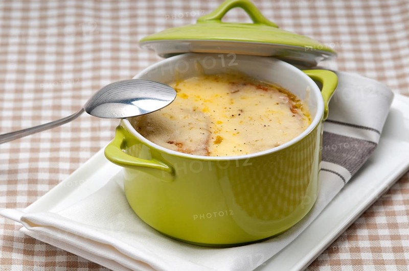 Onion soup on clay pot with melted cheese and bread on top