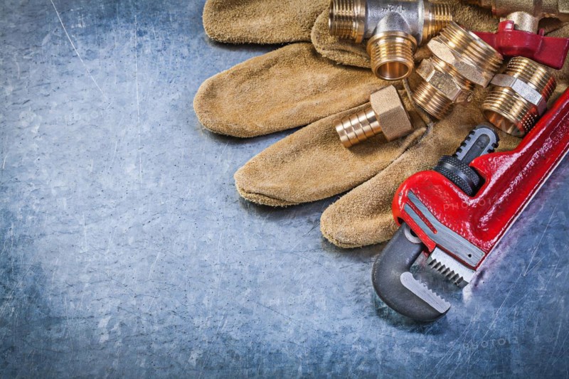 Adjustable wrench protective gloves brass pipe connectors on metallic background plumbing concept
