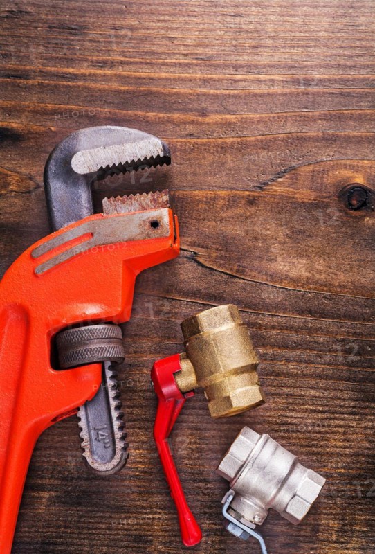 Plumbing fittings and monkey spanner on vintage wooden board