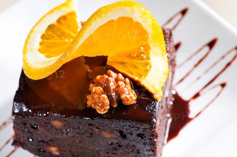 Fresh baked delicious chocolate and walnuts cake with slice of orance on top